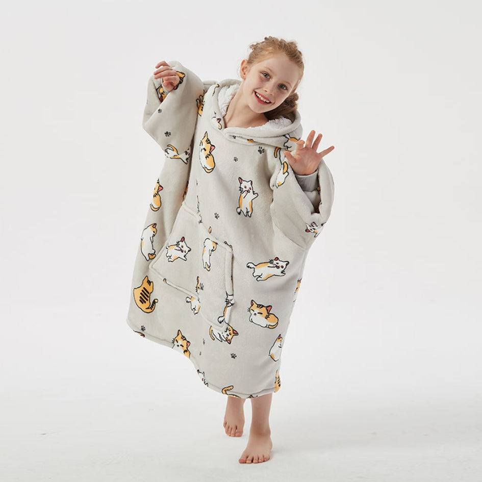 Kid wearing SNUGLFIT™ Hoodie Blanket with cute kitten print, showcasing cozy oversized fit and fluffy material.